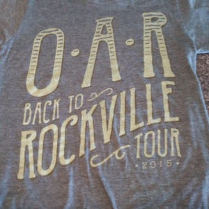 May include: Gray t-shirt with a white graphic print of the band "O.A.R." and the text "Back to Rockville Tour 2015."