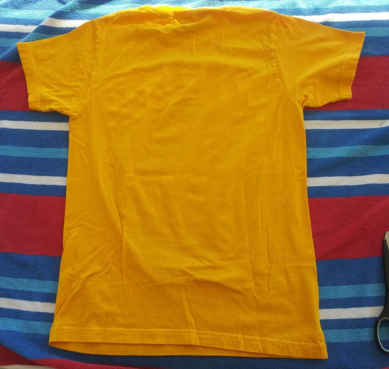 Pode incluir: Uma camiseta lisa amarela com mangas curtas.