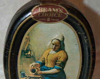 Puede incluir: Botella de licor Beam's Choice vintage con tapón dorado y cuerpo ovalado negro. La etiqueta presenta una pintura de una mujer vertiendo leche. La botella tiene 8 años.