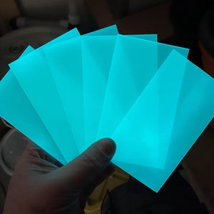 Puede incluir: Cinco l&aacute;minas de pl&aacute;stico acr&iacute;lico transl&uacute;cido azul turquesa. Las l&aacute;minas est&aacute;n apiladas una encima de la otra y brillan en la oscuridad.