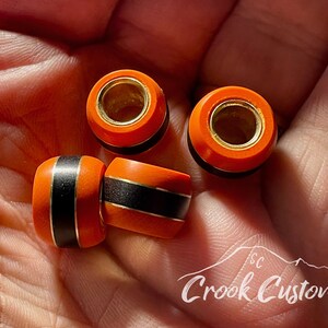 May include: Four orange and black wooden beads with gold accents. The beads have a smooth, polished finish and are perfect for jewelry making or other craft projects.