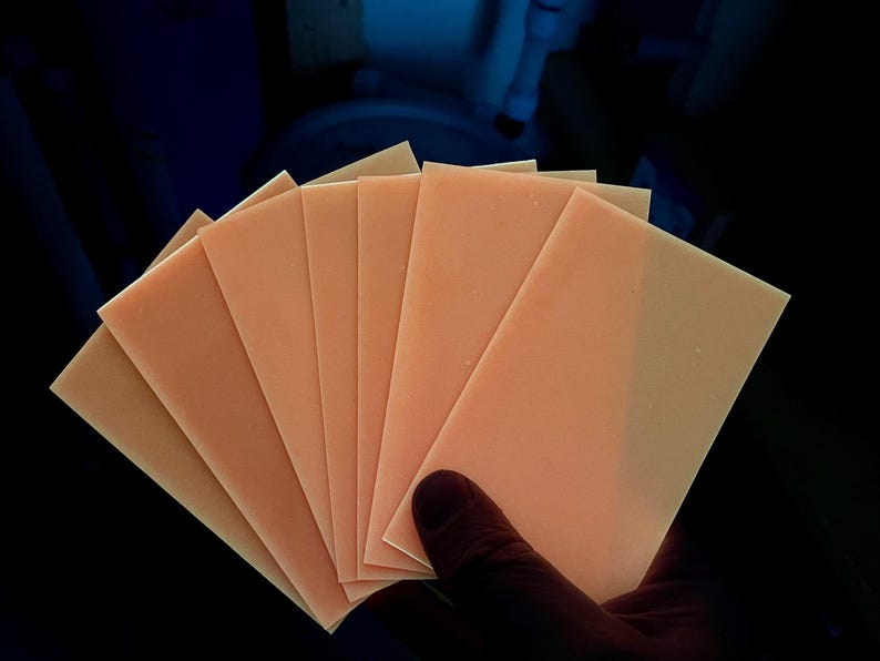 K&ouml;nnte beinhalten: Ein Stapel aus acht d&uuml;nnen, pfirsichfarbenen Bl&auml;ttern Papier.