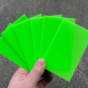 Op de afbeelding: Een set van zes heldergroene acrylplaten, gestapeld en in een hand gewaaid.