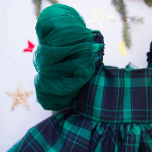 May include: A green plaid dress with a green tulle puff sleeve. The dress has a white background with the text "Lily Land" printed on the bottom.