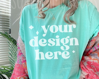 May include: A turquoise blue t-shirt with the text "your design here" printed in white. The shirt is being worn by a person with long brown hair.