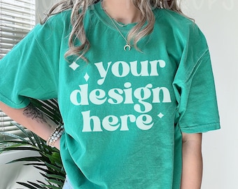 May include: A teal green t-shirt with the text "your design here" in white.