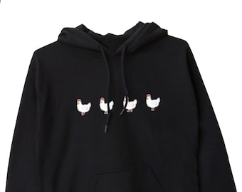 Puede incluir: Sudadera con capucha negra con un gráfico de cinco pollos blancos en fila en la parte delantera.