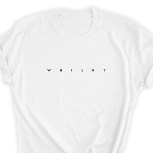 May include: White t-shirt with the word "WHISKY" printed in black, centered horizontally. The shirt has a crew neck and short sleeves, with the sleeves rolled up. The fabric appears to be cotton or a similar material.