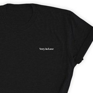 May include: Black t-shirt with the text "Very in Love" printed in white on the front.