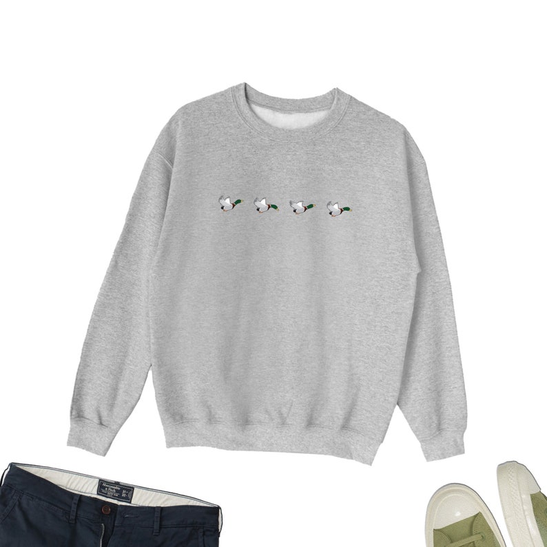 May include: A gray sweatshirt with a row of five embroidered ducks flying in a line across the chest.