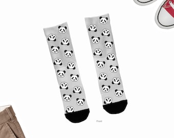 Könnte beinhalten: Ein Paar graue Socken mit einem schwarz-weißen Pandabären-Gesichtsmuster. Die Socken sind auf weißem Hintergrund mit einem Paar roten Converse-Schuhen und einer braunen Hose abgebildet.
