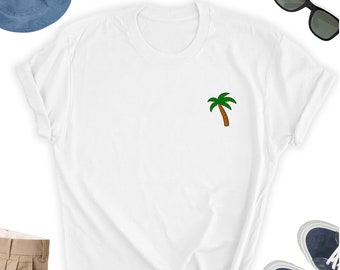 Könnte beinhalten: Weißes T-Shirt mit einem kleinen grünen Palmenbaum-Motiv auf der linken Brust.