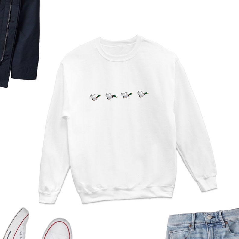 May include: White long-sleeved sweatshirt with a graphic of five ducks flying in a row.