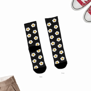 May include: A pair of black socks with a white and yellow egg pattern. The socks are shown from the front and back. The text "Front" and "Back" are written below the socks.