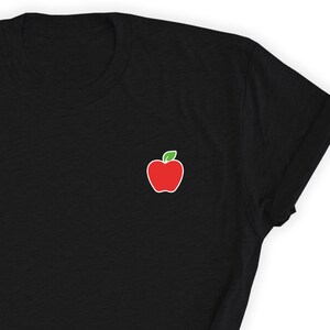 May include: A black t-shirt with a red apple graphic on the left chest.