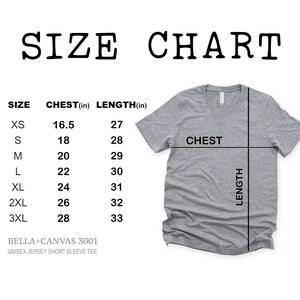 K&ouml;nnte beinhalten: Gr&ouml;&szlig;entabelle f&uuml;r ein Unisex-T-Shirt mit kurzen &Auml;rmeln, die Brust- und L&auml;ngenma&szlig;e in Zoll f&uuml;r die Gr&ouml;&szlig;en XS bis 3XL zeigt. Die Tabelle ist auf ein graues T-Shirt gedruckt.