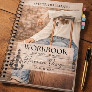May include: A spiral-bound workbook titled Daniela Baumanns Human Design Workbook Deine Reise zu dir selbst Basic Wissen, featuring a cover image of a person with a suitcase, alongside a gold pen and colorful sticky notes on a wooden surface.