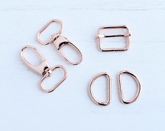 May include: A set of five rose gold metal hardware pieces for crafting. The set includes two swivel clasps, one rectangular buckle, and two D-rings.