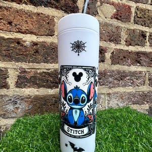 Puede incluir: Un vaso blanco con una ilustraci&oacute;n en blanco y negro de Stitch de Lilo & Stitch. La ilustraci&oacute;n es de estilo vintage con una telara&ntilde;a, un murci&eacute;lago y el texto "Stitch".