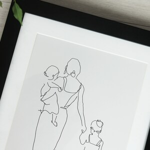 K&ouml;nnte beinhalten: Gerahmter Kunstdruck mit einer minimalistischen Strichzeichnung einer Mutter und zwei Kindern. Das Kunstwerk ist eine durchgehende schwarze Linie auf wei&szlig;em Hintergrund, die ein einfaches Familienportr&auml;t ergibt. Der Rahmen ist schwarz.