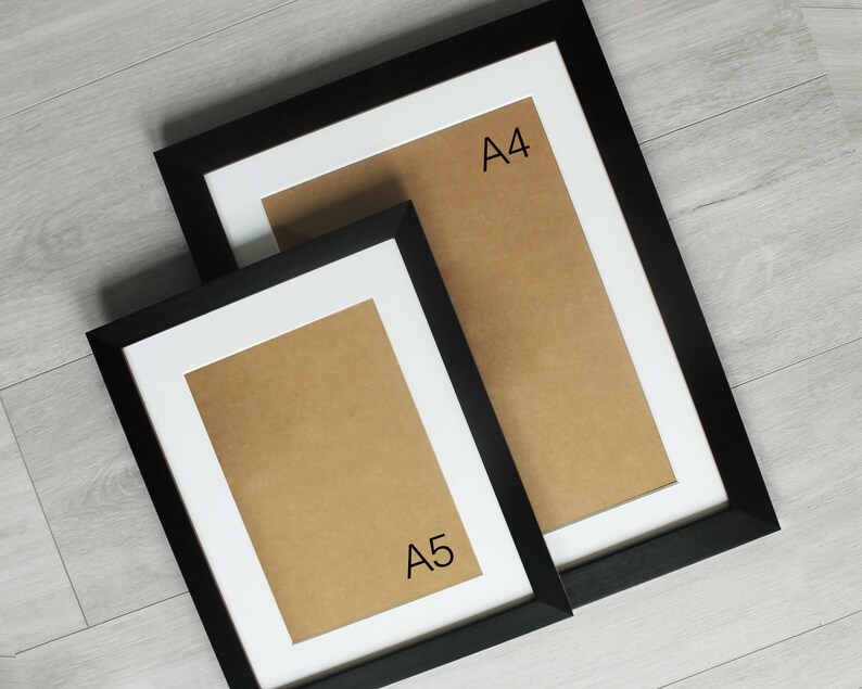 May include: Two black picture frames with white mats. The larger frame is labeled "A4" and the smaller frame is labeled "A5".
