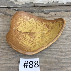 May include: A yellow ceramic leaf-shaped dish with a textured surface. The dish is numbered #88.