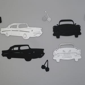 Puede incluir: Una colecci&oacute;n de formas de papel troquelado que incluye dos coches antiguos de perfil, uno blanco y otro negro, y dos coches antiguos de frente, uno negro y otro blanco. Tambi&eacute;n se incluyen dos pares de dados y cuatro flechas direccionales.