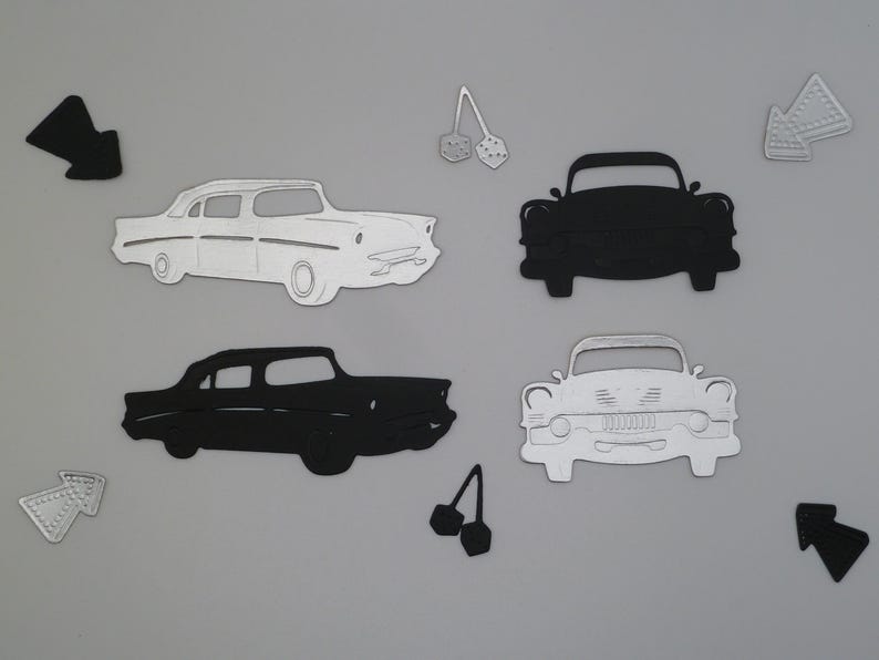 Puede incluir: Una colecci&oacute;n de formas de papel troquelado que incluye dos coches antiguos de perfil, uno blanco y otro negro, y dos coches antiguos de frente, uno negro y otro blanco. Tambi&eacute;n se incluyen dos pares de dados y cuatro flechas direccionales.