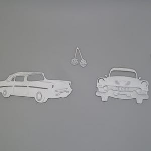 Puede incluir: Un conjunto de troqueles de metal plateado que incluye una vista lateral de un coche cl&aacute;sico, una vista frontal de un coche cl&aacute;sico, dos se&ntilde;ales en forma de flecha y un par de dados colgantes. Las formas son planas, met&aacute;licas y tienen relieves.