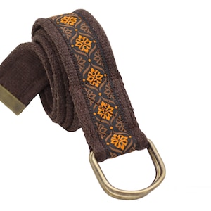 May include: A brown canvas belt with a decorative orange and black patterned trim and a brass buckle.
