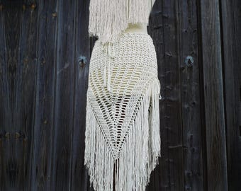 May include: A white crochet top and skirt set with fringe detailing. The top has a halter neckline and the skirt is a long, flowing A-line style.