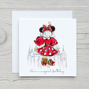 K&ouml;nnte beinhalten: Eine wei&szlig;e Karte mit einer roten und wei&szlig;en Illustration von Minnie Mouse vor dem Schloss von Aschenputtel. Der Text "Have a magical birthday" ist in schwarzer Kursivschrift am unteren Rand der Karte geschrieben.
