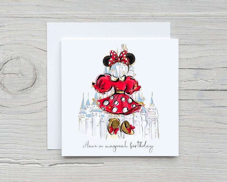 K&ouml;nnte beinhalten: Eine wei&szlig;e Karte mit einer roten und wei&szlig;en Illustration von Minnie Mouse vor dem Schloss von Aschenputtel. Der Text "Have a magical birthday" ist in schwarzer Kursivschrift am unteren Rand der Karte geschrieben.