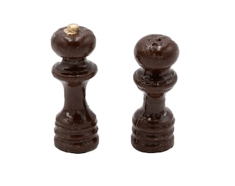 Op de afbeelding: Een set van twee bruine houten zout- en peperstrooiers met gouden toppen.
