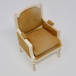 Puede incluir: Un peque&ntilde;o sill&oacute;n de madera blanco con un coj&iacute;n de terciopelo marr&oacute;n. El sill&oacute;n tiene un respaldo curvo y un dise&ntilde;o sencillo.