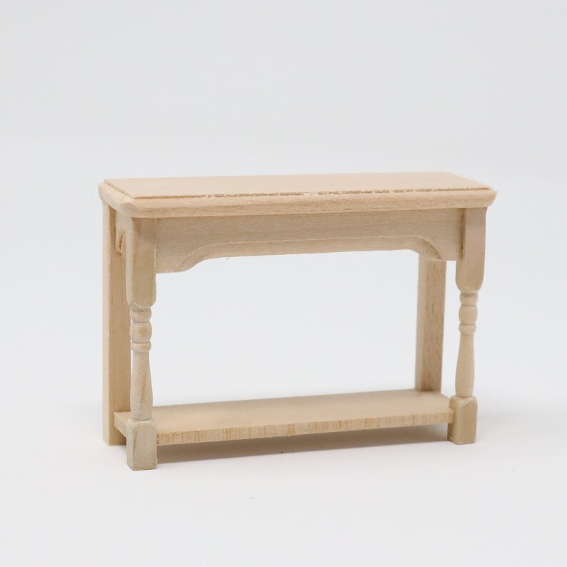 May include: A wooden console table with a simple design. The table has a rectangular top, two turned legs, and a lower shelf. The table is unfinished and ready to be painted or stained.
