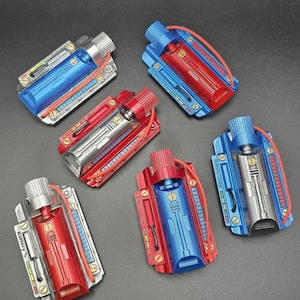 May include: Five rectangular battery-themed props featuring metallic finishes in blue, red, and silver. Each unit includes a cylindrical top knob, a central chamber, a thin red wire, and side panels labeled with Battery Usage or Battery % text.