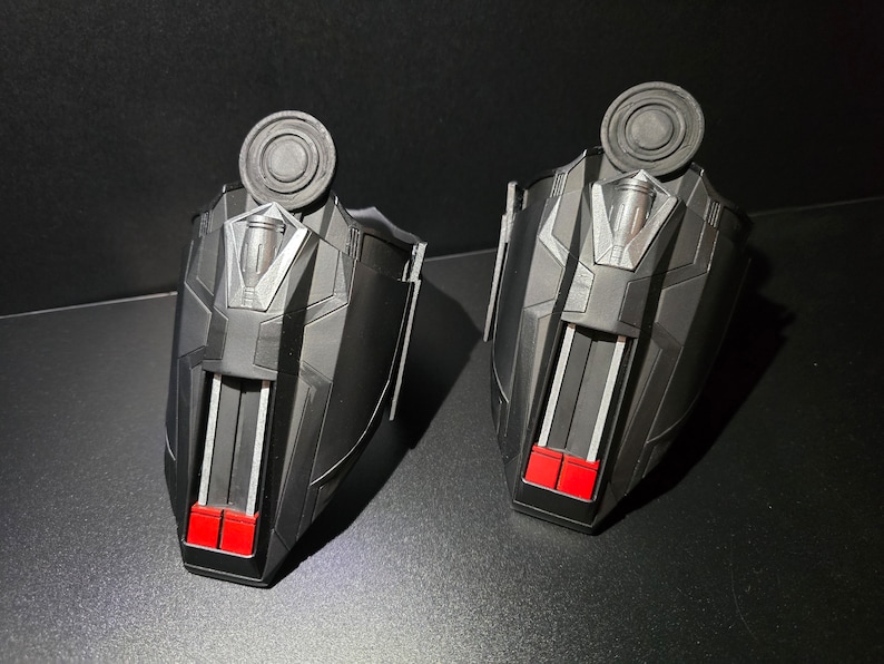 Puede incluir: Un par de lanzatelara&ntilde;as negros con detalles rojos y plateados. Los lanzatelara&ntilde;as tienen un dise&ntilde;o circular en la parte superior y un dise&ntilde;o rectangular en la parte inferior.