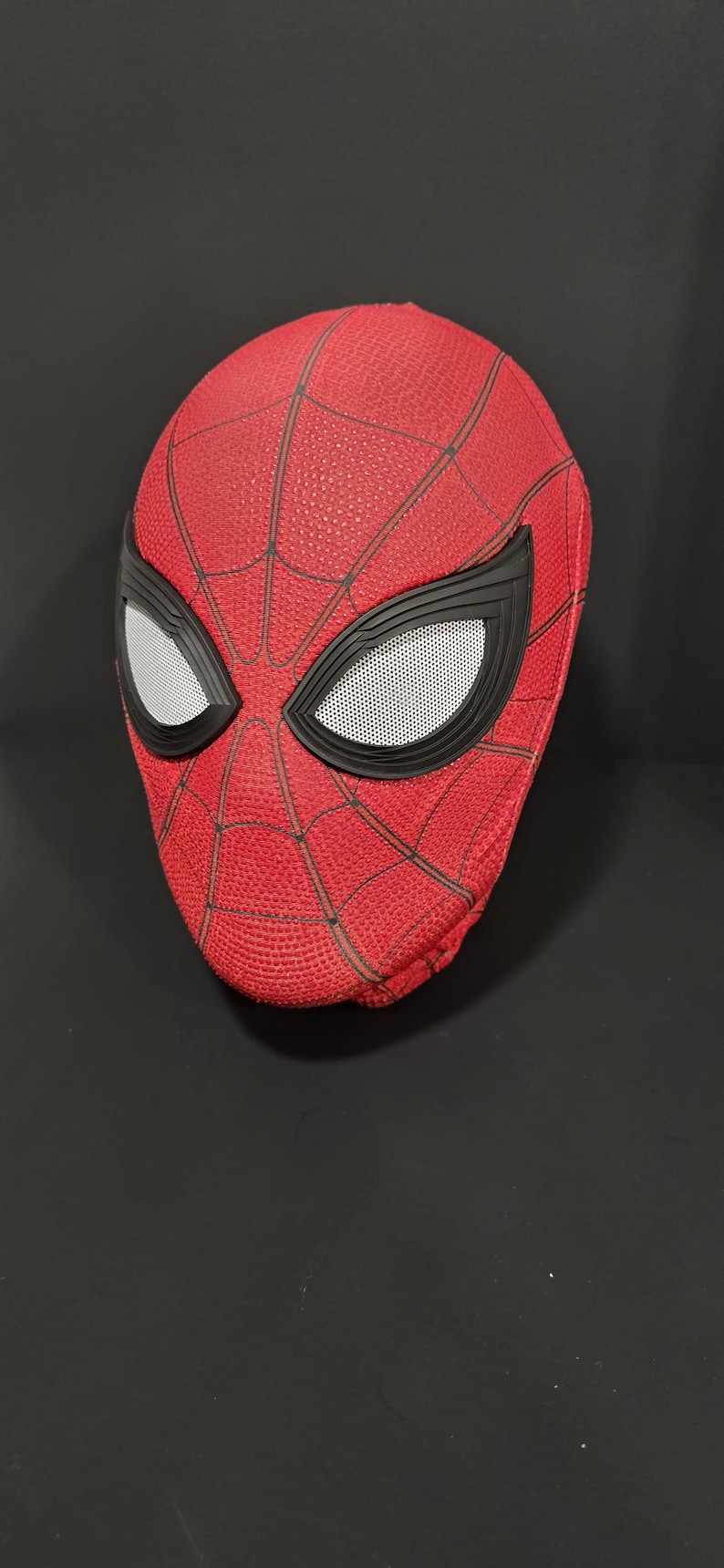 May include: A red Spider-Man mask with black webbing and eye frames. The eye lenses are white with a mesh pattern. The mask is a replica of the superhero's mask.
