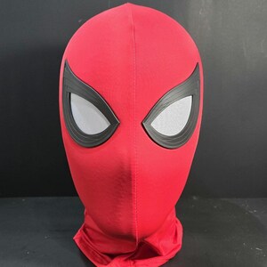 May include: A red Spiderman mask with black eye frames and mesh eye coverings. The mask is made of a soft fabric and covers the entire head and neck. The mask is a costume accessory.