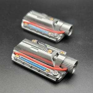 May include: Two rectangular silver mechanical components featuring a metallic finish, a prominent red wire, a row of small blue square accents, and a cylindrical knob on one end. Each piece is secured with small gold-colored screws along the sides.