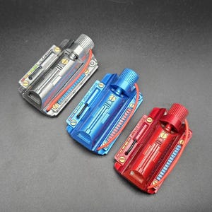 May include: Three rectangular metal battery pack props in silver, blue, and red. Each unit features a cylindrical knob, gold-colored screws, a red wire, and a printed label reading Battery Usage with a graphic indicator showing various colored bars.