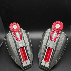 Puede incluir: Dos piezas de brazo de juguete de pl&aacute;stico negro y rojo con un c&iacute;rculo rojo en la parte superior. Las piezas de brazo tienen un dise&ntilde;o de rayas plateadas y rojas.