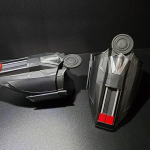 Puede incluir: Un par de artilugios de juguete de pl&aacute;stico negro con detalles rojos y plateados. Los artilugios tienen una forma redonda en forma de disco en la parte superior y una forma rectangular en la parte inferior.