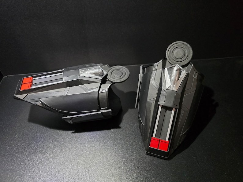 Puede incluir: Un par de artilugios de juguete de pl&aacute;stico negro con detalles rojos y plateados. Los artilugios tienen una forma redonda en forma de disco en la parte superior y una forma rectangular en la parte inferior.