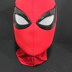 May include: A red fabric mask with black eye surrounds and white mesh eye coverings. The mask is a full head covering, likely for cosplay or costume use.