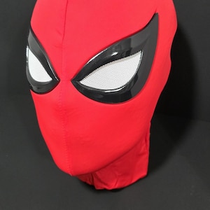May include: A red fabric mask with black eye coverings and white mesh eye inserts. The mask is designed to cover the entire head and face. The mask is likely for cosplay or costume use.
