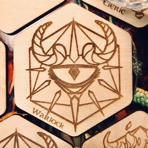 May include: Hexagonal wooden coaster with a laser-etched design. The design features an eye with horns and geometric shapes, with the word "Warlock" etched below. The coaster is light brown in colour.