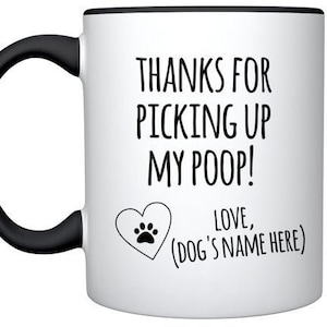 May include: White ceramic coffee mug with a black handle and rim. The mug has a black paw print heart and the text "THANKS FOR PICKING UP MY POOP! LOVE, (DOG'S NAME HERE)"