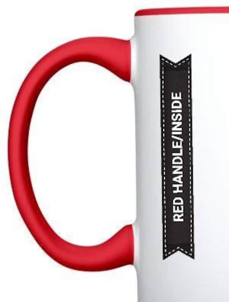 May include: White ceramic mug with a red rim and a red handle. The mug has a black banner with the text "RED HANDLE/INSIDE" printed on it.
